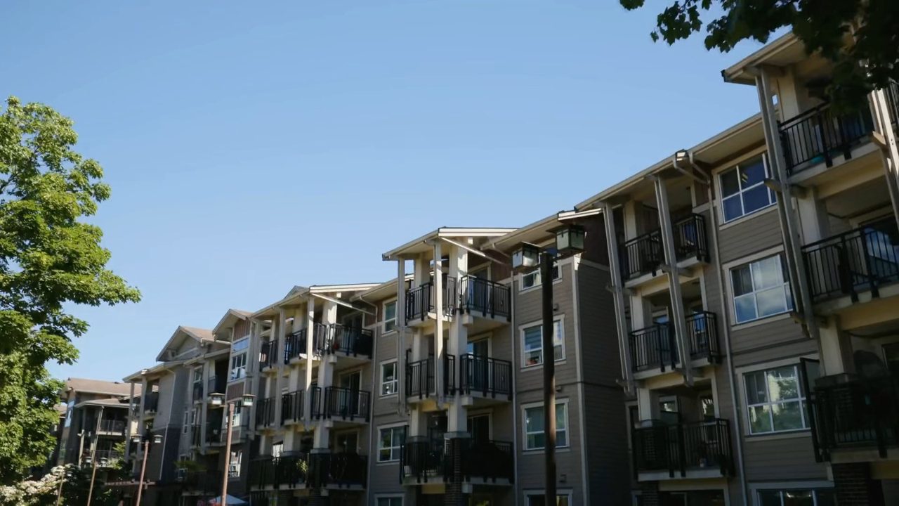 A finished apartment block from street level against a clear blue sky.